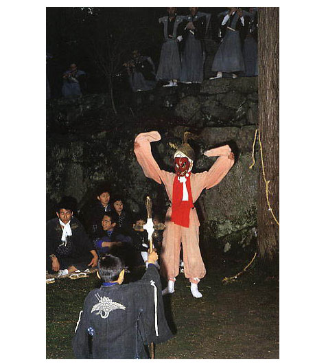 天満社例祭神事の様子を撮影した写真。剣を持った人とお面を被った人が写っている。