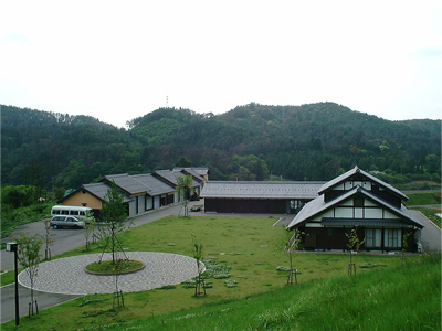 奥に山が見えて、手前にコの字型に建物が並んでいる写真(かみなか農楽舎)