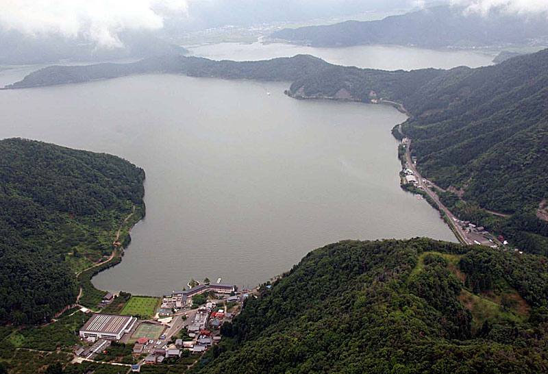 山々に囲まれた真ん中に湖が見える上空から撮影された写真(水月湖)