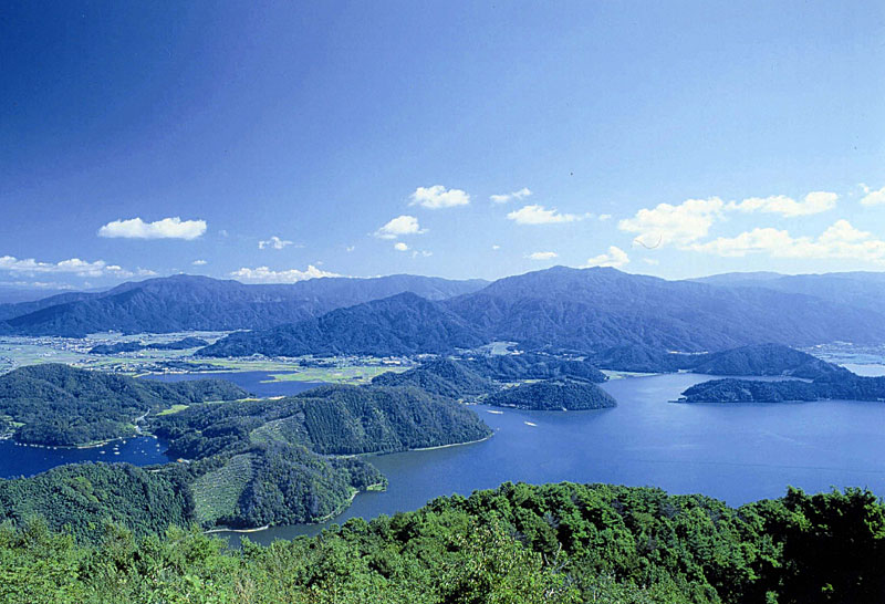 青い空と緑の山々があり、その下に湖が写っている写真(三方五湖)