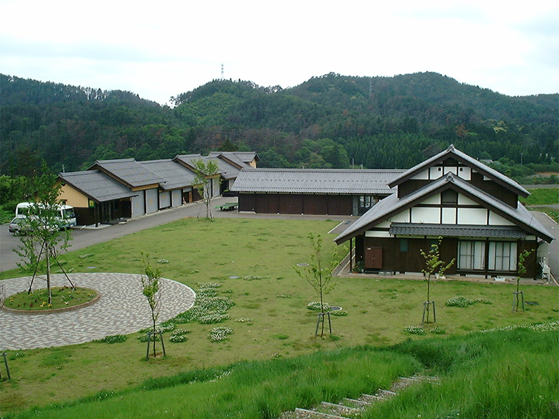 奥に山が見えて、手前にコの字型に建物が並んでいる写真(かみなか農楽舎)