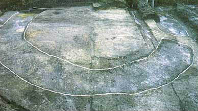 灰色の地面に陸橋および周溝が検出されている場所に白い印が形取られている日笠松塚古墳の写真