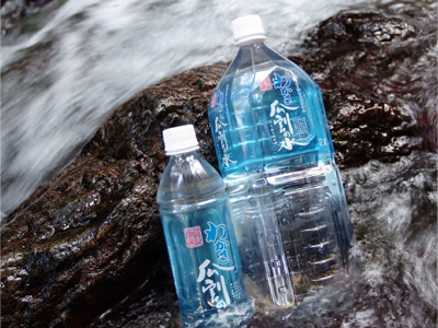 岩の上を流れる水に「わかさ瓜割の水」と書かれたラベルが貼られている大小のペットボトルが1本ずつ写っている写真