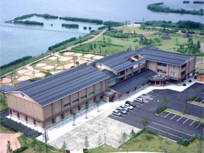 湖の隣に建つL字型の建物と駐車場を上から写した写真（福井県三方青年の家）