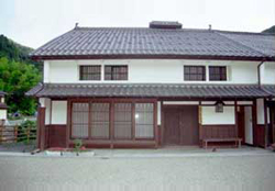 古い形式の日本家屋だが、壁は白く、板戸も新しい様子の写真