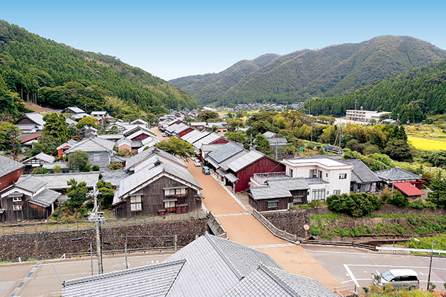 奥に山と空が広がり、高いところから見下ろしている熊川の町並みの写真