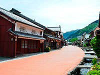 晴れた天気の元左に建物が立ち並びオレンジ色の道とその脇に流れる小さな川の中ノ町の写真