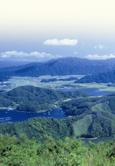 上部に白い雲と青い空、緑の山々と山の合間に青い湖が写っている風景写真