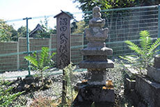 古い石塔とその左に立てられた沼田氏の供養塔と書かれた木の看板の写真