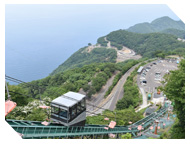 海が見える場所の山にある駐車場からケーブルカーが運行している様子の写真