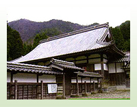 瓦屋根のお寺の建物と瓦屋根がある塀がある写真